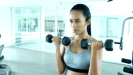 Mujer-asiática-joven-deportiva-ejercicio-con-pesas-en-el-gimnasio.-Ejercicio-de-la-mujer-en-el-gimnasio.-Concepto-de-reacción-y-deporte.-4k-resolución.