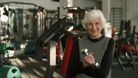 Mujer-Senior-con-la-pesa-de-gimnasia-en-gimnasio