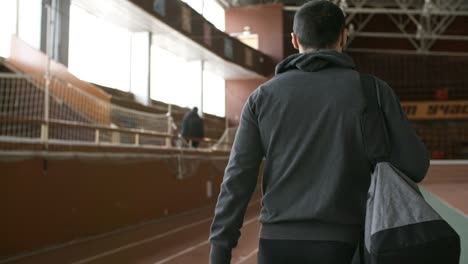 Determined-Sportsman-in-Hoodie-Walking-in-Indoor-Stadium