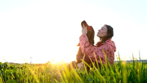 Woman-playing-with-dog-at-sunset,-young-girl-with-pet-sitting-on-grass-and-relaxing-in-nature