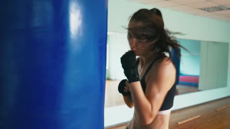 Beautiful-Mixed-Race-Kickboxing-woman-training-punching-bag-in-fitness-studio-fierce-strength-fit-body-kickboxer-series