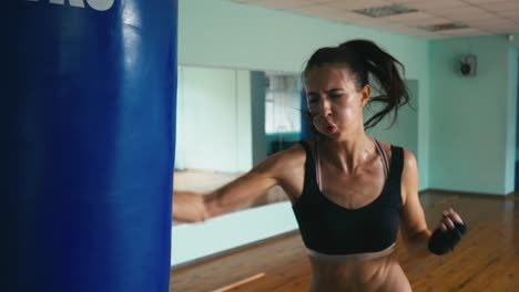 Schöne-gemischte-Rennen-Kickboxen-Frau-Training-Boxsack-im-Fitness-Studio-heftige-Stärke-passen-Körper-Kickboxer-Serie