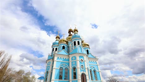 Orthodox-temple,-Clouds-above-the-temple,-golden-domes,-Timelapse,-exterior,-a-view-from-below,-Blue-temple,-blue-church,-Against-the-sky,-Golden-domes