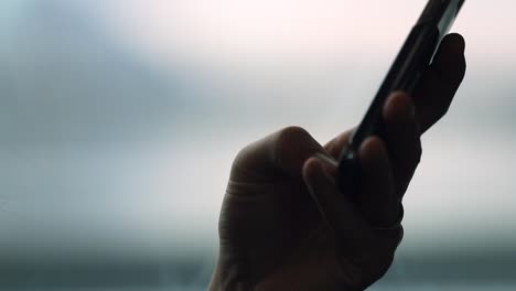 Close-up-of-person-holding-cellphone-device-while-on-a-moving-train.-Rack-focus-to-smartphone-with-background-blurred-motion