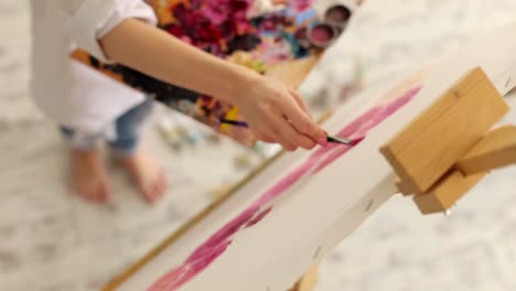 Frau-malt-Bild-auf-Leinwand-mit-Ölfarben-im-studio