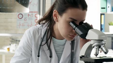 Mujer-investigadora-utilizando-microscopio-en-laboratorio