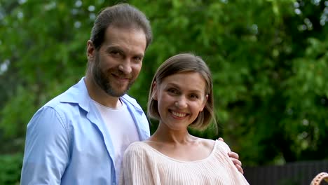 Pretty-lady-putting-picnic-basket-on-table,-man-hugging-her,-looking-at-camera