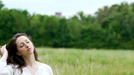 Mujer-profundamente-relajada-en-campo-verde-toca-su-cabello-con-ojos-cerrados-unidad