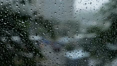 Gotas-de-lluvia-sobre-fondo-de-cristal-azul.-Calle-bokeh-luces-fuera-de-foco.-Otoño-fondo-abstracto.