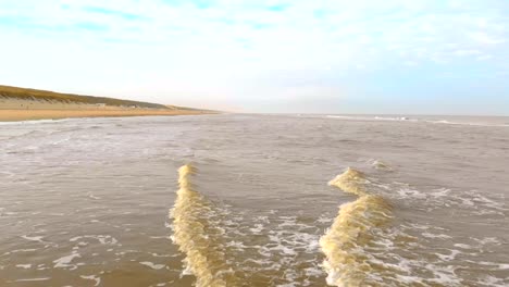 Luftaufnahme.-Slow-Motion-Flug-über-das-Meer-und-die-Wellen,-die-kommen-zum-Ufer-in-den-sonnigen-Morgen.-Niederlande-Zandvoort.-Nordsee.-Uferlinie