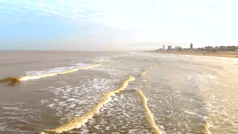 Luftaufnahme.-Slow-Motion-Flug-über-das-Meer-und-die-Wellen,-die-kommen-zum-Ufer-in-den-sonnigen-Morgen.-Niederlande-Zandvoort.-Nordsee.-Uferlinie