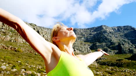 Senior-woman-standing-with-arms-outreached-at-countryside-4k