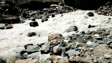 Mountain-river-flows-out-from-under-the-glacier,-a-beautiful-panoramic-landscape,-slow-motion.-Group-of-tourists-on-excursions,-camera-movement