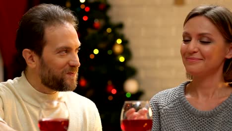 Happy-couple-drinking-wine-and-embracing,-romantic-date-at-Christmas,-closeup