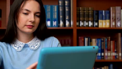 chica-guapa-con-tableta-de-ordenador-en-la-biblioteca-o-en-la-oficina.