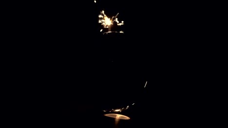 Burning-sparkler-behind-a-glass-ball-on-a-black-background.