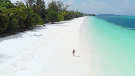 Aerial:-woman-walking-on-tropical-beach,-scenic-turquoise-water-and-white-sand,-Pasir-Panjang-Kei-Island,-Moluccas,-Indonesia,-paradise-travel-destination