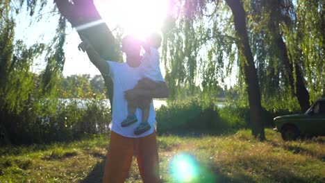 Joven-padre-e-hijo-caminando-en-el-parque-y-apuntando-a-algo.-Papá-sosteniendo-en-las-manos-de-su-hijo-y-disfrutar-de-la-naturaleza-en-verano.-Familia-feliz-pasar-tiempo-juntos.-Lenta-de-cerca