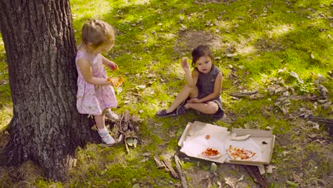 Zwei-Mädchen-im-Park-Pizza-essen.