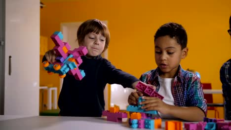 Two-diverse-kids-arguing-over-toy-in-kindergarten