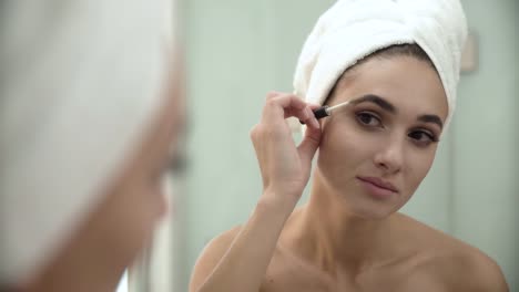 Belleza-maquillaje.-Cepillar-las-cejas-en-el-espejo-de-baño-de-mujer