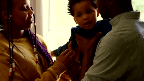 Side-view-of-young-black-parents-holding-their-baby-in-a-comfortable-home-4k