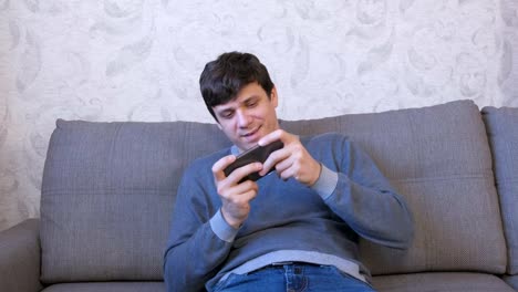 Mann-spielt-Spiel-auf-seinem-Handy-auf-dem-Sofa