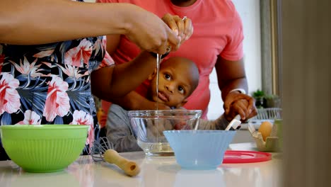 Mother-cracking-eggs-and-son-looking-at-her-in-kitchen-at-home-4k