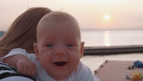 Baby-girl-in-mothers-hands-outdoor-at-sunset