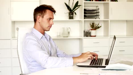 young-man-sitting-at-working-desk-with-laptop