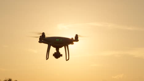 CLOSE-UP-LENS-FLARE-SILHOUETTE:-Filming-drone-with-camera-flying-over-golden-sun