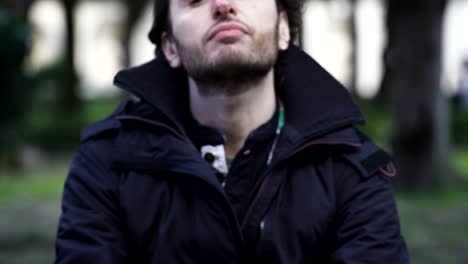 close-up-on-lonely-and-desperate-man-sitting-at-the-park,-reflects-on-his-life