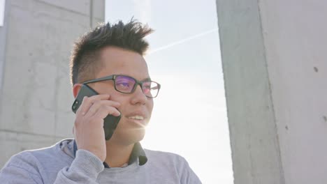 Un-hombre-joven-hablando-por-un-teléfono-exterior