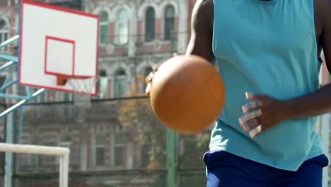 Starke-männliche-afroamerikanische-Kerl-spielt-Basketball-am-Sportplatz