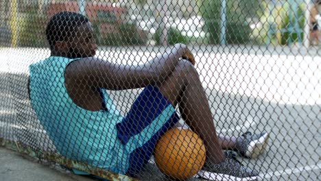 Jugador-de-baloncesto-africano-americano-cansadas-relajante-después-de-partido-en-el-estadio,-afición