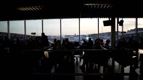 Tourists-waiting-for-boarding-at-departure-lounge,-people-sitting-in-airport