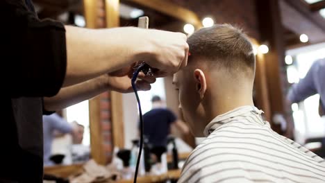 Barber-cuts-hair-with-electric-razor-to-young-customer