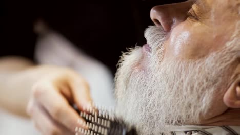 Barber-dries-and-combs-beard-of-mature-man