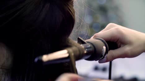 Hands-of-stylist-curling-hair-with-curling-tongs