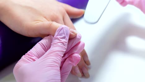 closeup-beautician-filing-nails-to-customer-in-beauty-salon