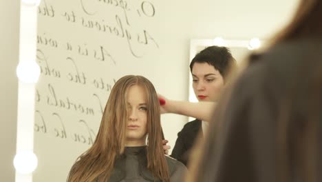 Peluquería-mujer-peinado-cabello-largo-con-cepillo-para-el-pelo-durante-el-corte-de-peluquería.-Cerrar-haciendo-espejo-frontal-de-corte-de-pelo-mujer-en-salón-de-belleza-peluquería