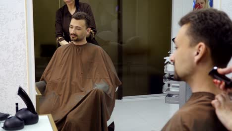 Friseur-schneidet-Haare-gut-aussehender-Mann-mit-Elektrorasierer