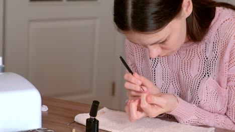 Mujer-pone-la-segunda-capa-de-goma-laca-rosa-en-uñas-con-pincel.