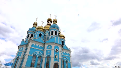 Orthodox-temple,-Clouds-above-the-temple,-golden-domes,-Timelapse,-exterior,-a-view-from-below,-Blue-temple,-blue-church,-Against-the-sky,-Golden-domes