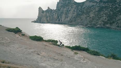 Aerial-view-woman-walking-against-ocean-and-rocks