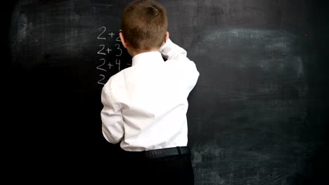 Junge-Mathe-Ausdruck-auf-einer-Tafel-zu-lösen.-Kreatives-Konzept-zurück-zu-Schule-und-Studium.-Vorschule