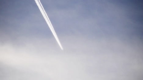 Footage,-using-a-telephoto-lens-of-an-airplane-flying-high-in-the-clouds.