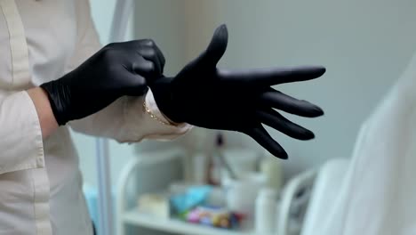 La-cosmetóloga-pone-negro-guantes-de-protección-en-la-sala-de-cosmetología.