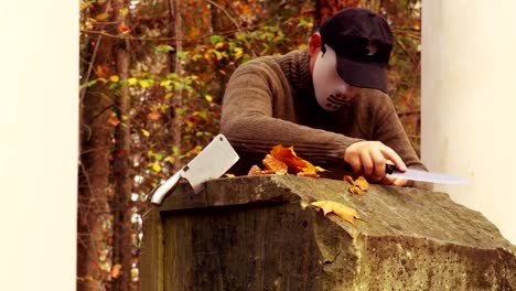 Mann-mit-scary-Halloweenmaske-schärfen-Messer-im-park