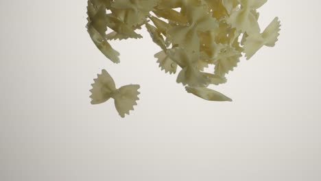 SLOW-MOTION:-Farfalle-Pasta-falls-under-water-on-white-background